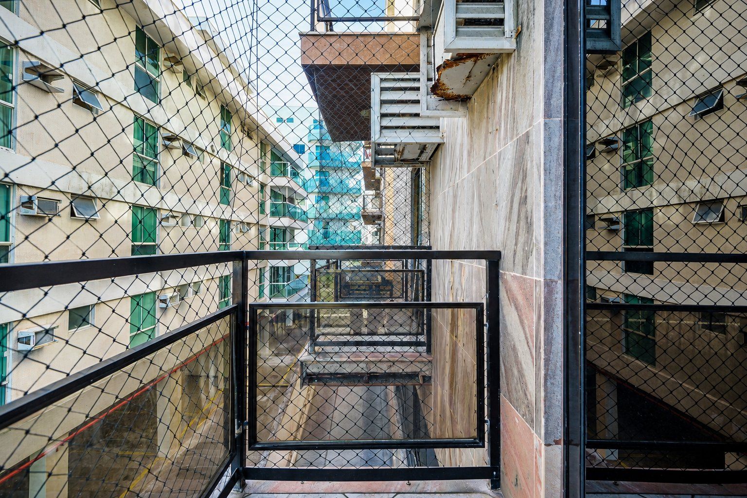 A multi-story building with a central staircase surrounded by a metal fence.