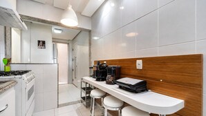 Una cocina moderna con estufa a gas, cafetera y taburetes de bar.