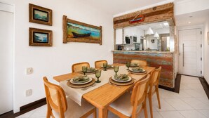 Een eetgedeelte met een houten tafel voor vier personen, omringd door rieten stoelen.