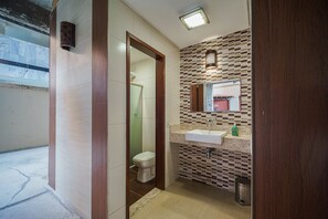 Ein Badezimmer mit gefliestem Boden, Toilette, Waschbecken und Spiegel.
