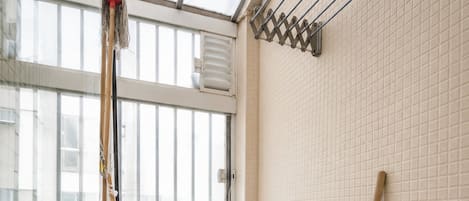 Ein Badezimmer mit Fenster, Waschbecken, Spiegel, Schrank und Reinigungsmittel.