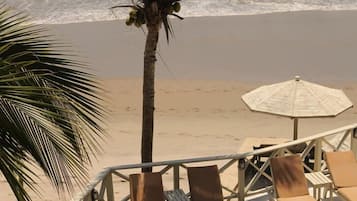 Un espace aménagé au bord de la piscine, avec des chaises longues et un palmier.