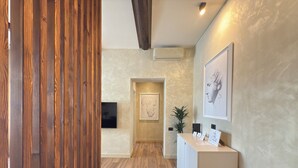 A reception area with a wooden panel wall, a reception desk, a mounted flat-screen TV, a framed artwork, and a potted plant. - Pantheon Urbes Collection (Roma)