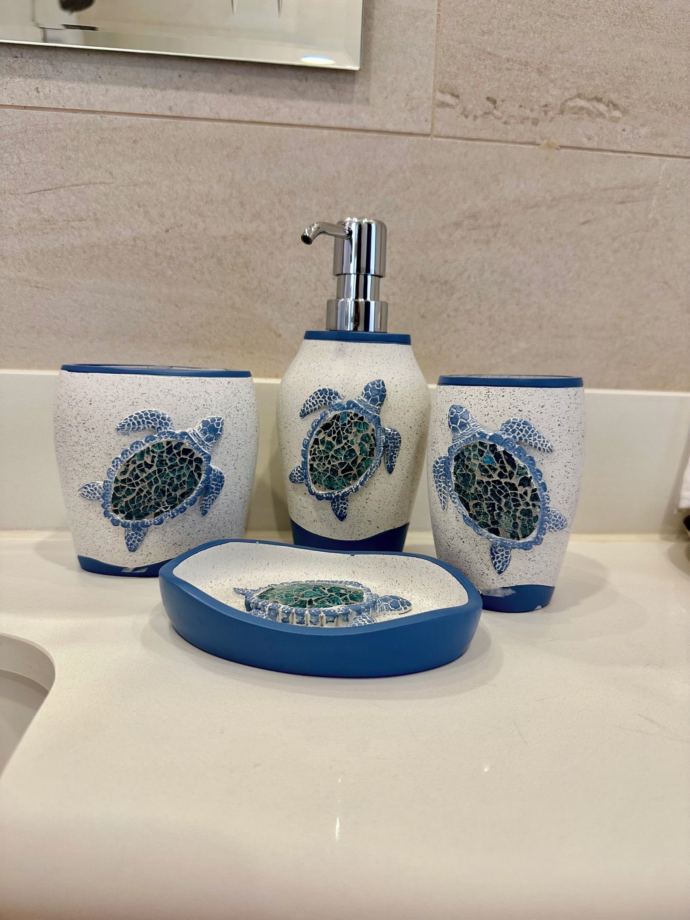 A bathroom sink area with a faucet, three ceramic cups with turtle designs, and a blue-rimmed bowl.