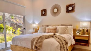 A bedroom with a large bed, a wooden headboard, a view through a sliding glass door, and two bedside tables with lamps. - 3-bedroom house Casa Tortuga (Coco)