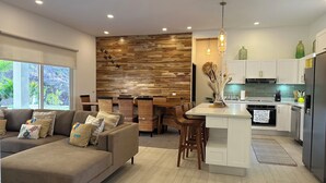 A modern kitchen with white cabinets, a central island, and a dining area with wicker chairs. - 3-bedroom house Casa Tortuga (Coco)