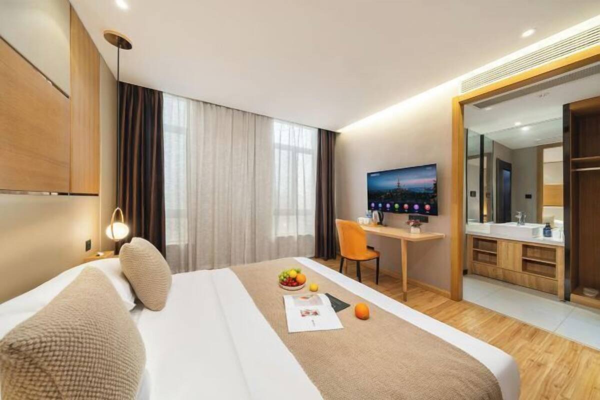 A hotel room with a bed, a desk, a TV, and a bathroom.
