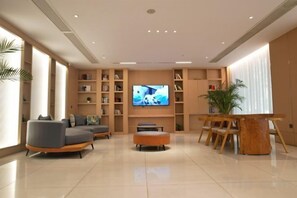 A modern living room with a flat-screen TV, a sofa, a coffee table, and built-in bookshelves. - Starway Hotel (Bozhou Wanda Plaza) (Bozhou)