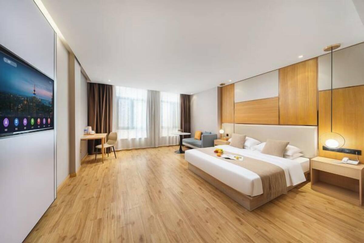 A modern hotel room with a large bed, a desk, and a television.