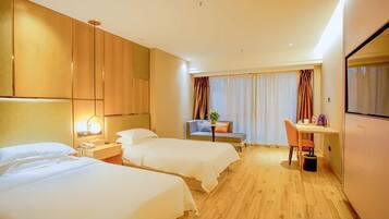 Habitación de hotel con dos camas, un escritorio, una silla, un televisor y una ventana con cortinas.