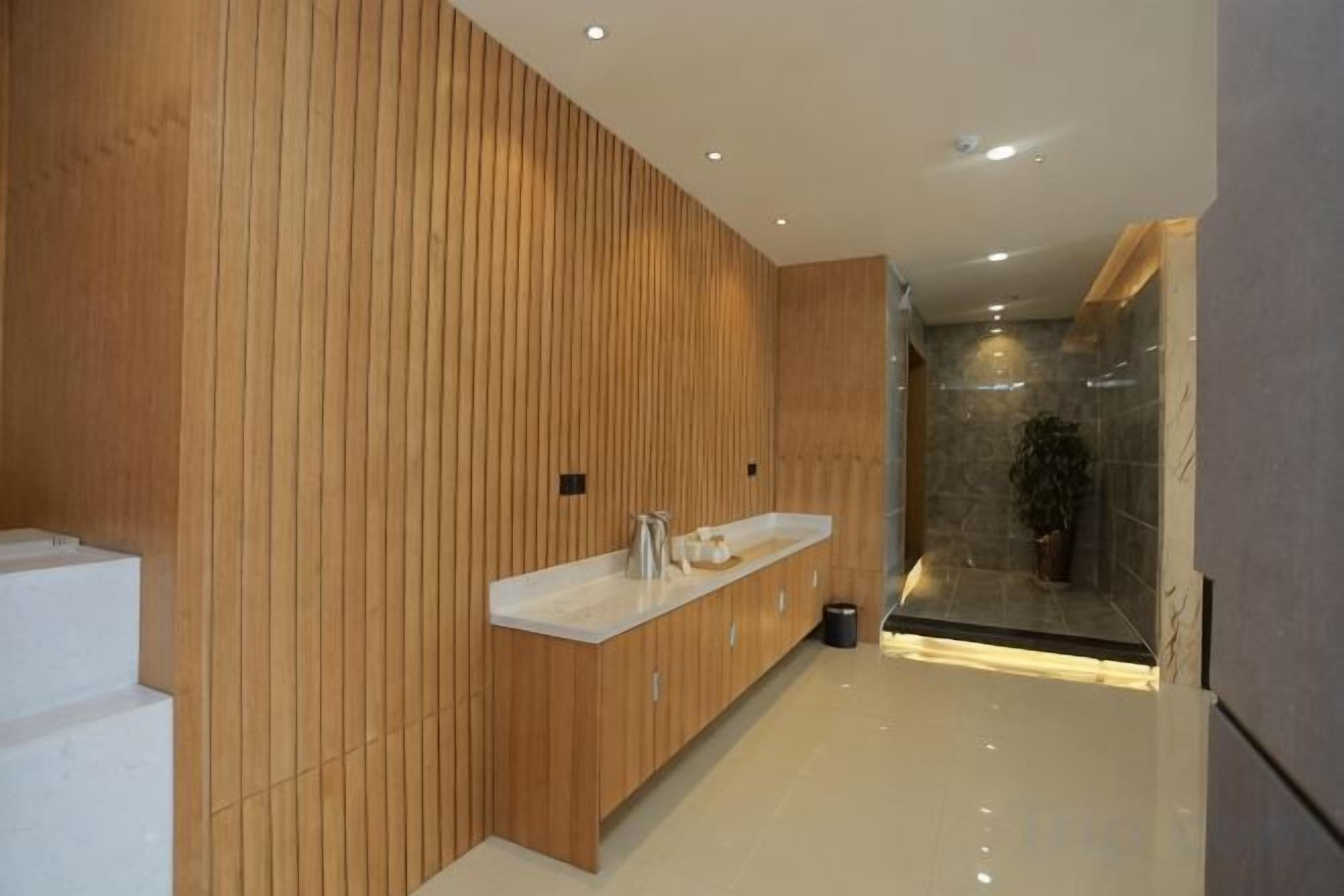 Un baño moderno con paneles de madera, una encimera blanca y una cabina de ducha de vidrio.