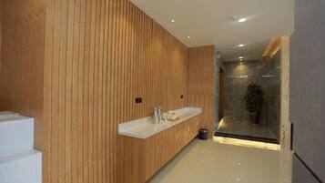 Un baño moderno con paneles de madera, una encimera blanca y una cabina de ducha de vidrio.