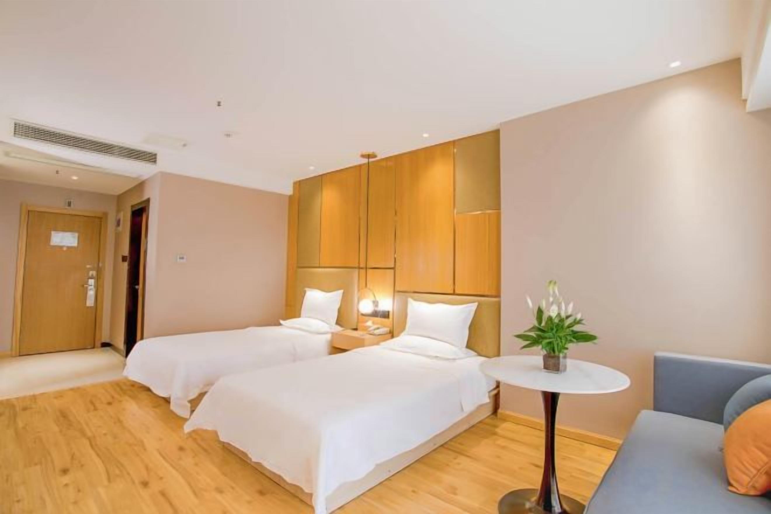 Una habitación de hotel con dos camas, una mesita y un sofá.