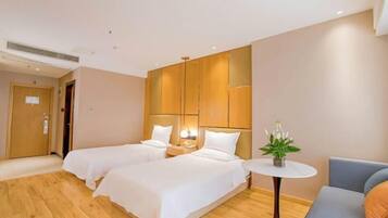 Una habitación de hotel con dos camas, una mesita y un sofá.