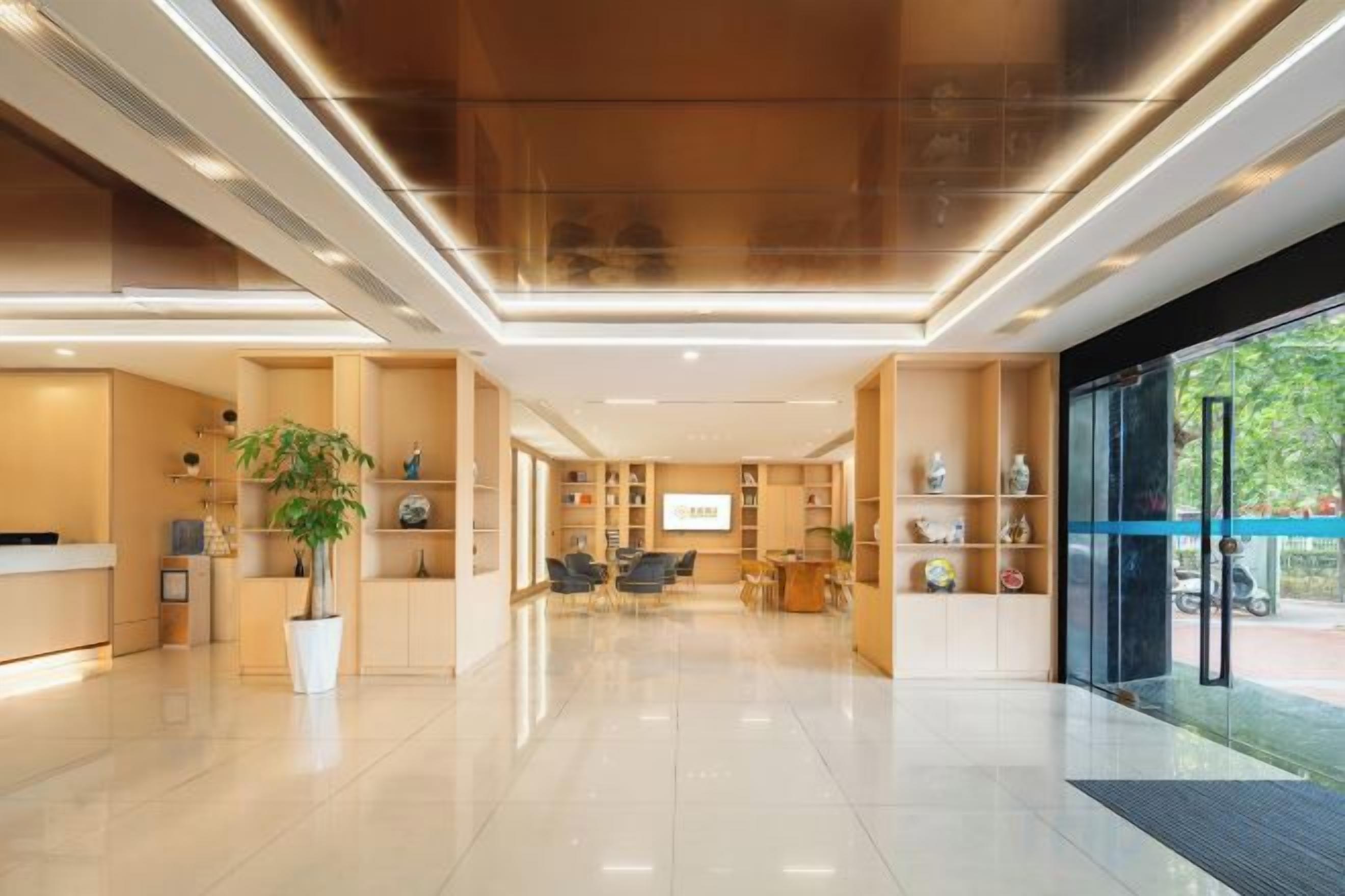 Un hall d’hôtel moderne comprenant un comptoir d’accueil, un espace salon et une grande fenêtre donnant sur l’extérieur.
