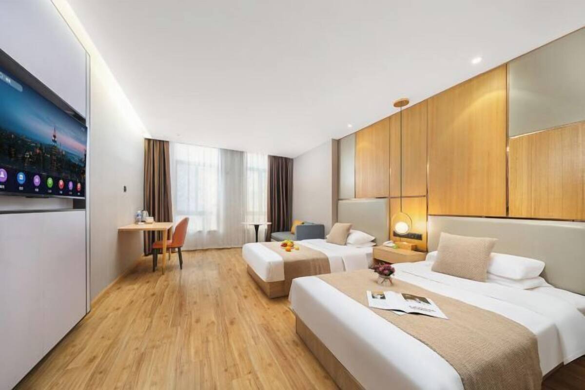 A hotel room with a bed, a desk, a chair, and a TV.