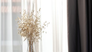 A glass-top table with a vase of dried plants, a cup, and a book. - Acropol Golden Suites (Neos Marmaras)