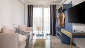 A modern living room with a sofa, coffee table, and a TV mounted on the wall. - Acropol Golden Suites (Neos Marmaras)