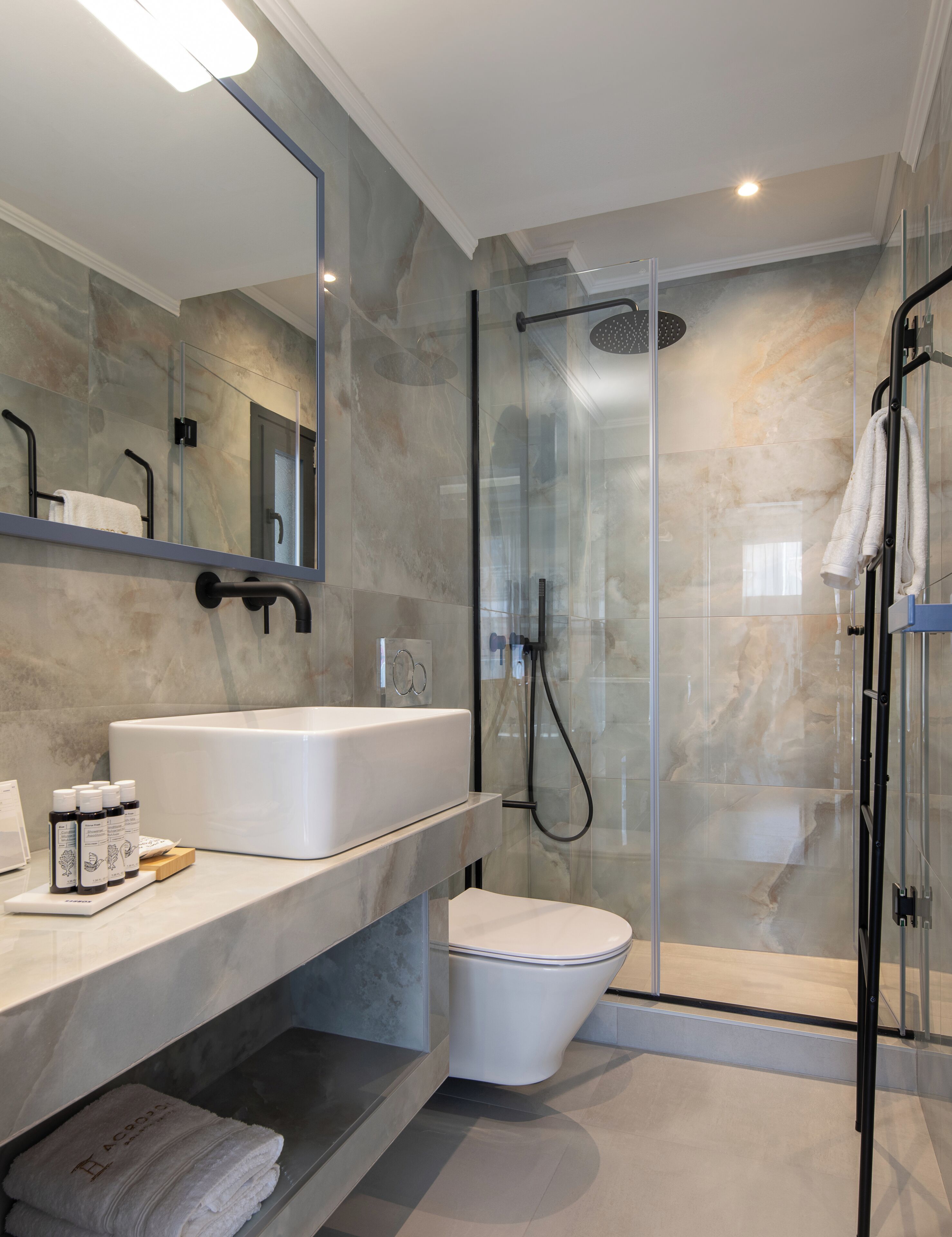 A modern bathroom with a glass-enclosed shower, a white sink, and a large mirror.