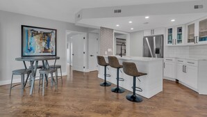 A modern kitchen with white cabinetry, a central island, and bar stools.