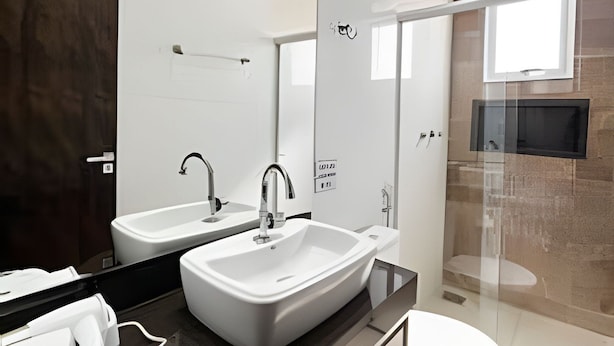 A modern bathroom with two sinks, a toilet, and a glass shower enclosure. - Castelo Branco (Patos de Minas)