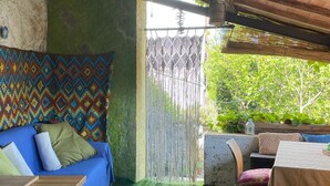 A cozy outdoor seating area with a blue sofa, a wooden table, and a patterned wall.