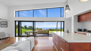 Een moderne keuken met een groot eiland, houten kastjes en uitzicht op de omgeving.