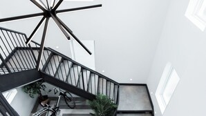 Una escalera en espiral con un diseño geométrico en el suelo, una bicicleta y una planta en maceta.
