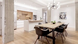 Una cocina moderna con armarios blancos, una isla de madera y un comedor con mesa de madera y sillas negras.