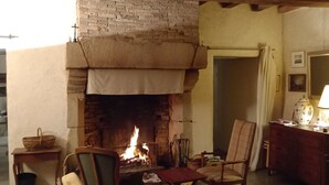 A cozy room with a fireplace, wooden furniture, and a patterned rug. - BRETON MANOR (Theix-Noyalo)