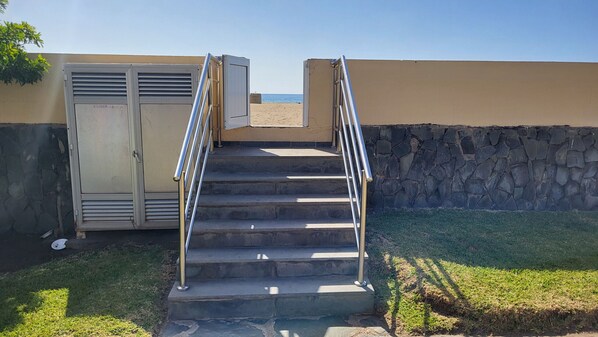 A set of outdoor stairs leading to a building with a stone wall and a beach view. - Ciaboga Front Line By CanariasGetaway (San Bartolomé de Tirajana)