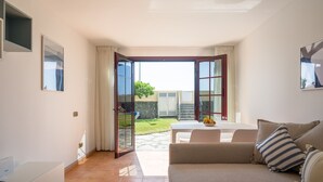 Una sala de estar moderna con un sofá, una mesa de centro con una planta, y un comedor con una mesa y sillas.