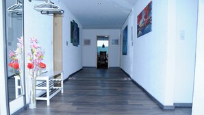 A hallway with wooden flooring, a bench, and a vase with flowers.