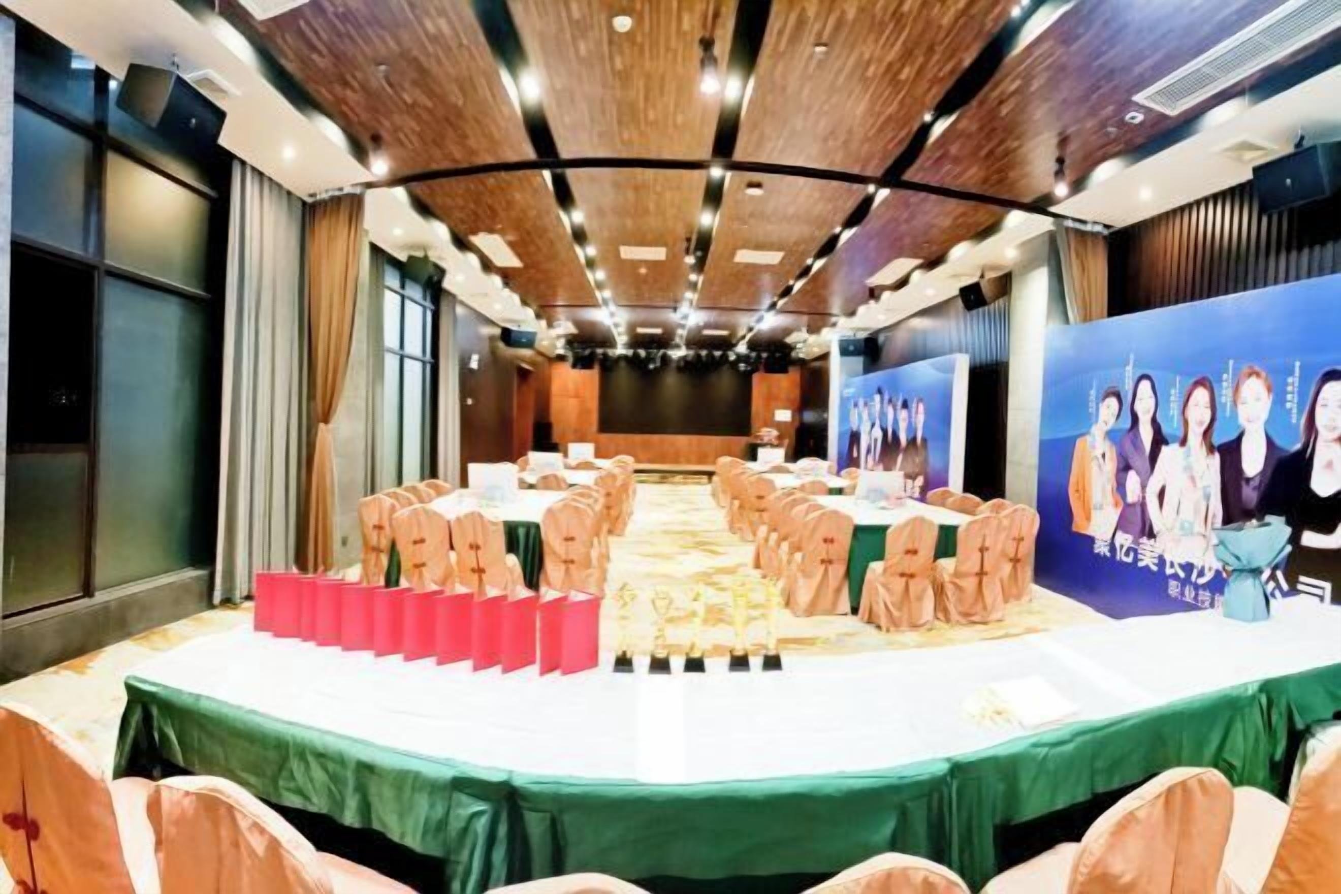 A conference room with a long table, chairs, and a stage with a backdrop.