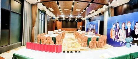 A conference room with a long table, chairs, and a stage with a backdrop.