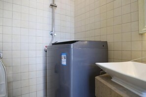 A bathroom with a white tiled wall, a grey trash bin, and a white sink. - Tianyi International Hotel (Nandujiang Meilan Airport Branch) (Haikou)