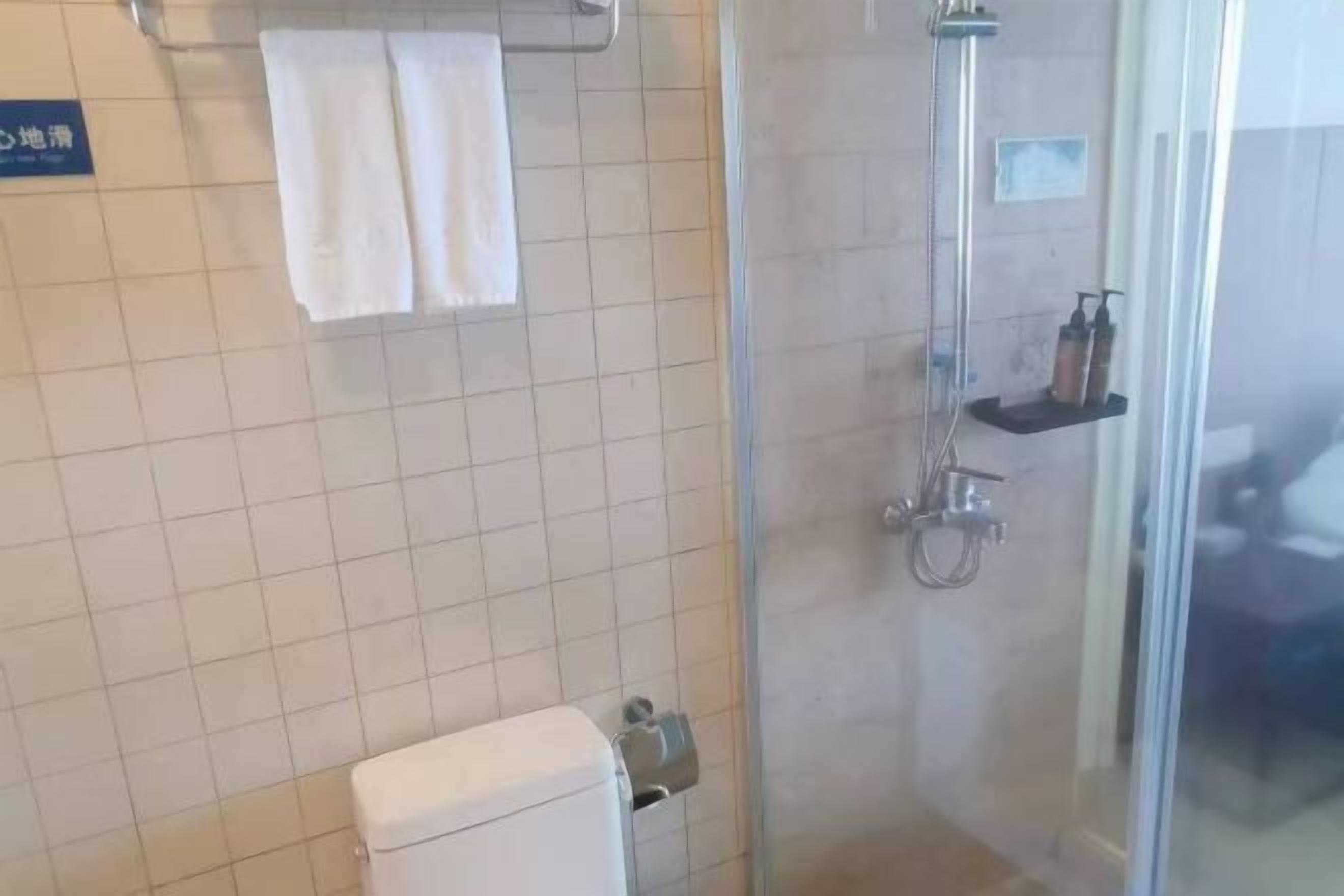Un baño con inodoro, cabina de ducha de vidrio y un perchero para toallas.