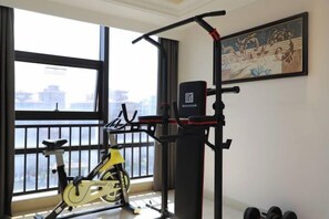 A gym with a stationary bike, a pull-up bar, and dumbbells.
