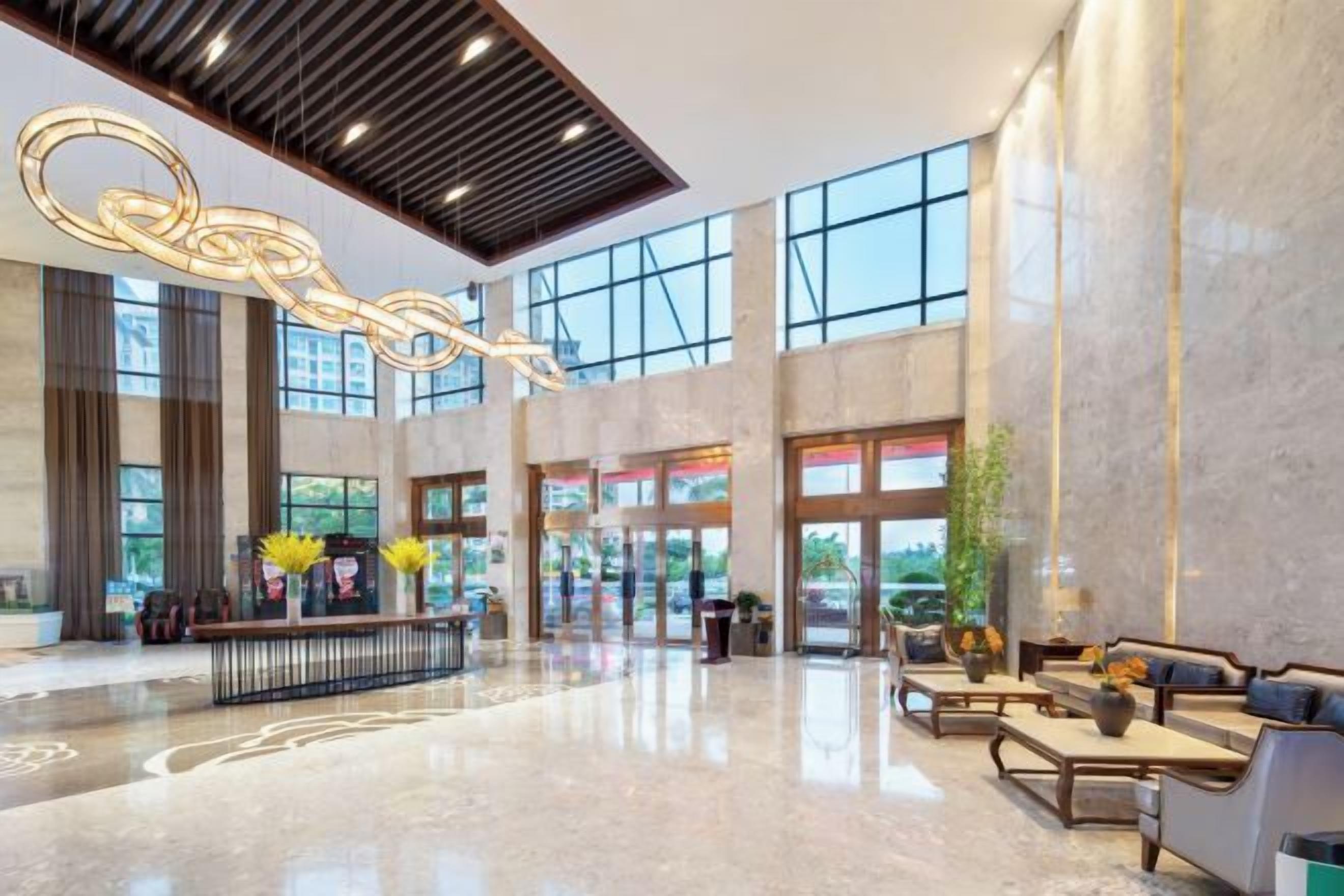 A spacious lobby with a high ceiling, large windows, and a reception desk.