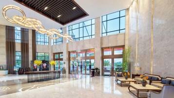 A spacious lobby with a high ceiling, large windows, and a reception desk.