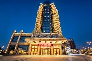 A modern hotel building with a prominent entrance and signage indicating 24-hour service. - Tianyi International Hotel (Nandujiang Meilan Airport Branch) (Haikou)
