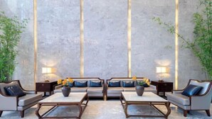 A modern room with a sofa set, two tables, and lamps. There are plants on either side of the room. - Tianyi International Hotel (Nandujiang Meilan Airport Branch) (Haikou)