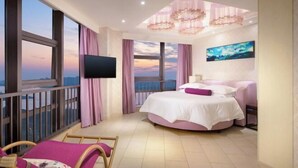 A bedroom with a large bed, a TV, a painting, and a balcony with a view. - Tianyi International Hotel (Nandujiang Meilan Airport Branch) (Haikou)