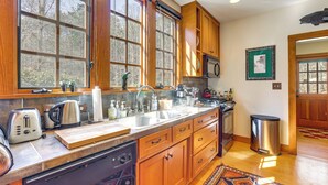 A kitchen with wooden cabinets, a stainless steel sink, and a built-in dishwasher. - Dock, Canoe & Patio: Lakeside Cottage in Alabama (Trussville)