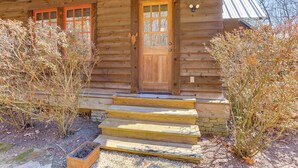 A wooden cabin with a front door, steps, and a stone foundation. - Dock, Canoe & Patio: Lakeside Cottage in Alabama (Trussville)