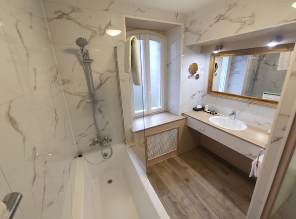 A modern bathroom with a bathtub, shower, and sink. - Le Pavillon Saint Martin (Souillac)