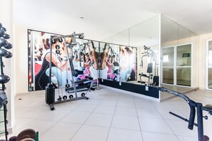 Un gimnasio con equipo de ejercicio, un espejo grande y piso de baldosas.