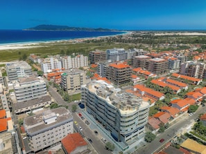 Vista aérea de una zona residencial costera con edificios modernos, una playa y cielos despejados.