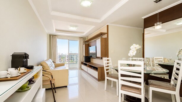 A modern hotel room with a sofa, dining table, chairs, a coffee machine, and a TV. - Cf02 Cobertura 200m da Praia das Dunas (Cabo Frio)