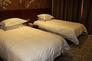 Two single beds with white linens, a wooden headboard, and a patterned carpet.